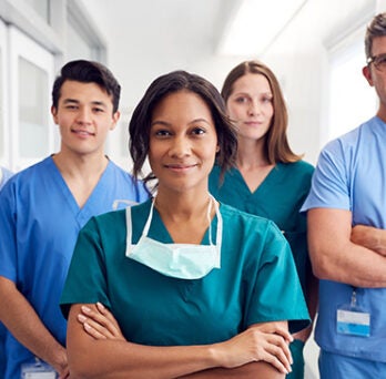 Five nurses standing in a line, smiling at the camera 